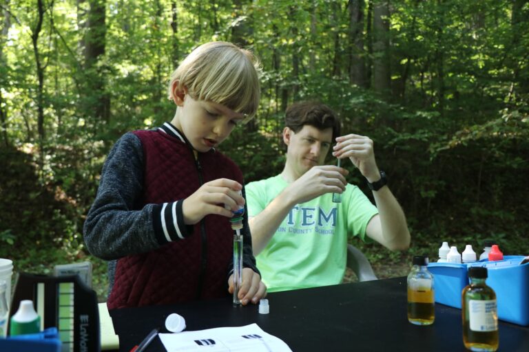 Father and son testing water samples from creek for chemicals.