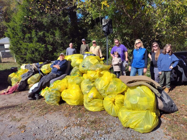 Volunteers with dozens of yellow trash bags collected at a cleanup