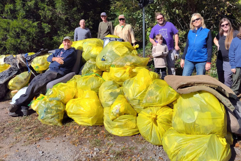 Volunteers with dozens of yellow trash bags collected at a cleanup